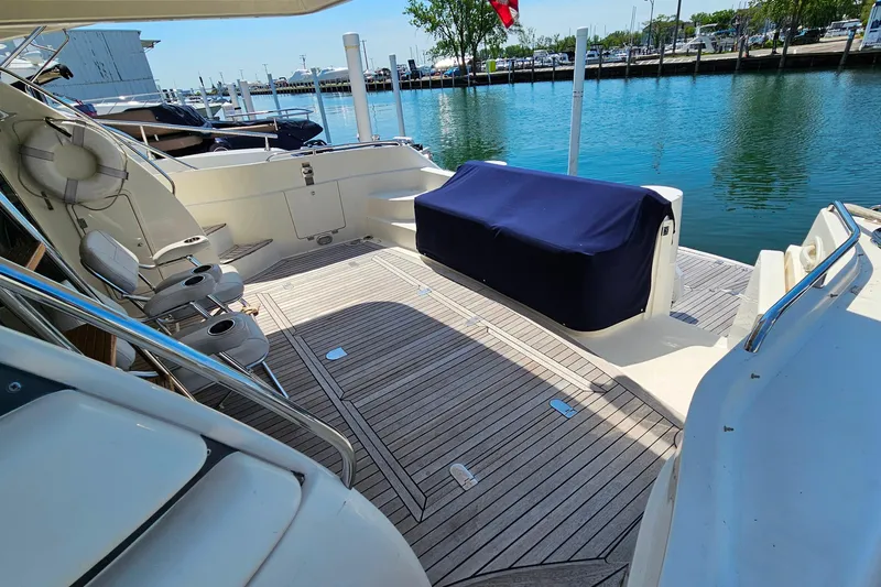 Slide: The Image of Sunseeker Manhattan 62 yacht deck with seating, docked by calm waters, 1998 model. - 6