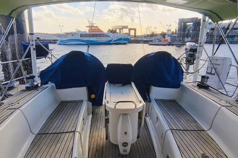 Slide: The Image of Cockpit view of a 2003 Bavaria 49 sailboat docked at a marina with a ferry in the background. - 14