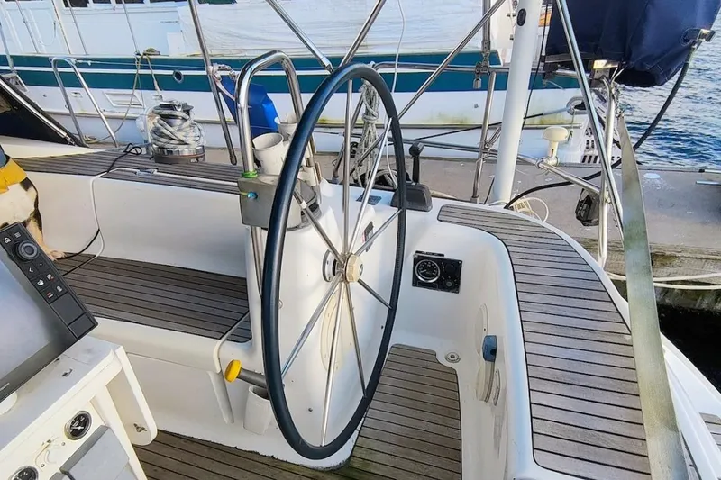 Slide: The Image of Steering wheel of a 2003 Bavaria 49 yacht, docked by the water. - 15