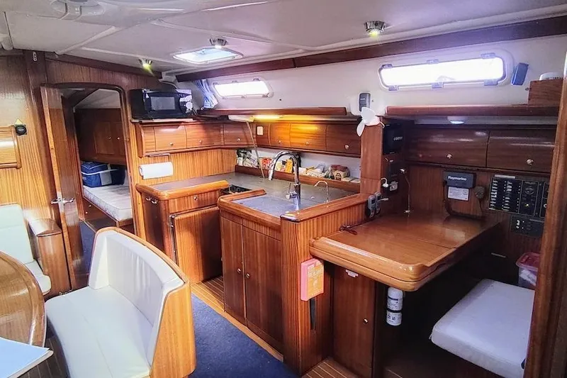 Slide: The Image of Interior of a 2003 Bavaria 49 yacht featuring a cozy wooden kitchen and seating area. - 20