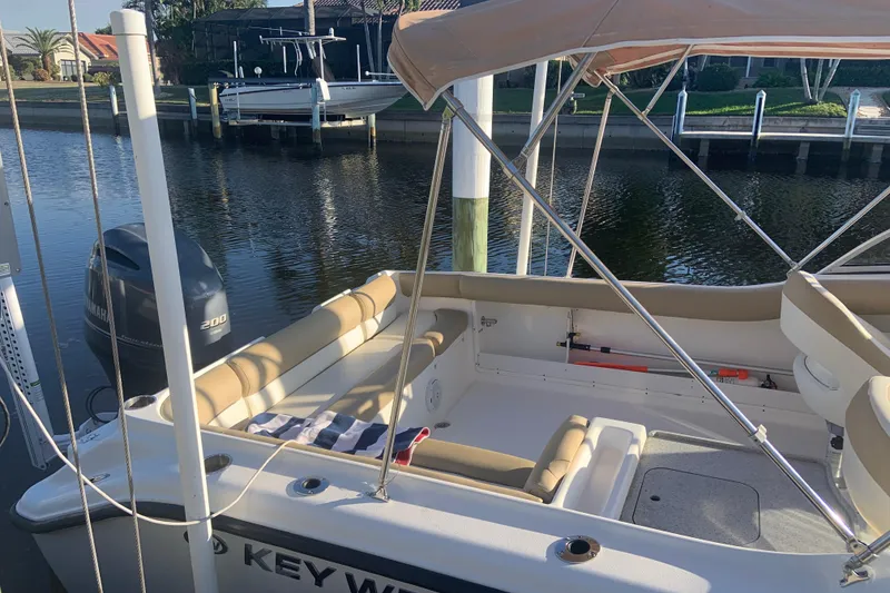 Slide: The Image of 2016 Key West 239 DFS boat docked, featuring beige seating and Yamaha outboard motor. - 4