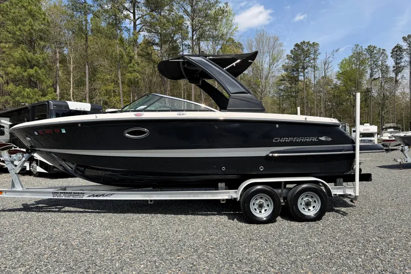 Slide: The Image of 2019 Chaparral 257 SSX boat on trailer, parked outdoors with trees in background. - 25