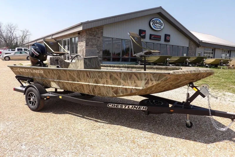 The Image of 2026 Crestliner 1760 Retriever SC boat on trailer, camo design, parked outside marine center. - 1