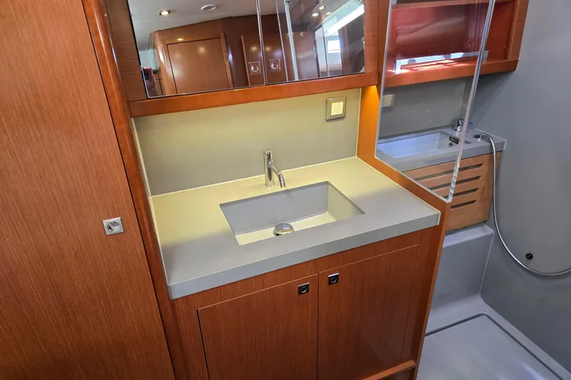 Slide: The Image of Modern bathroom vanity in 2016 Beneteau Oceanis 55 yacht, featuring sleek sink and wooden cabinetry. - 37