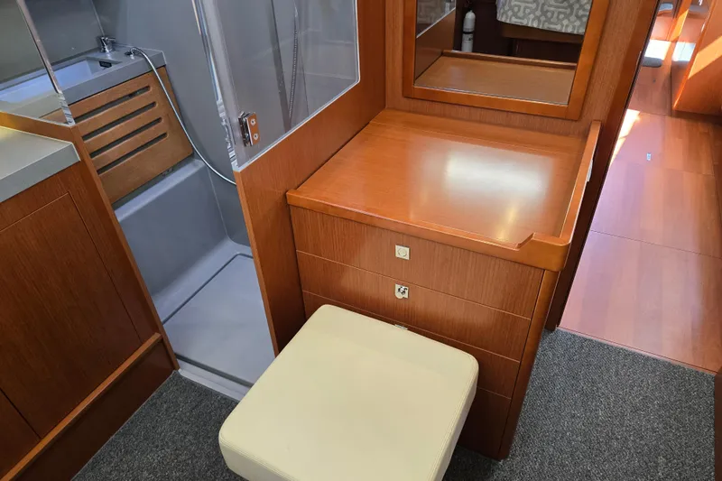 Slide: The Image of Interior of 2016 Beneteau Oceanis 55 yacht featuring a wooden vanity and cushioned stool. - 38