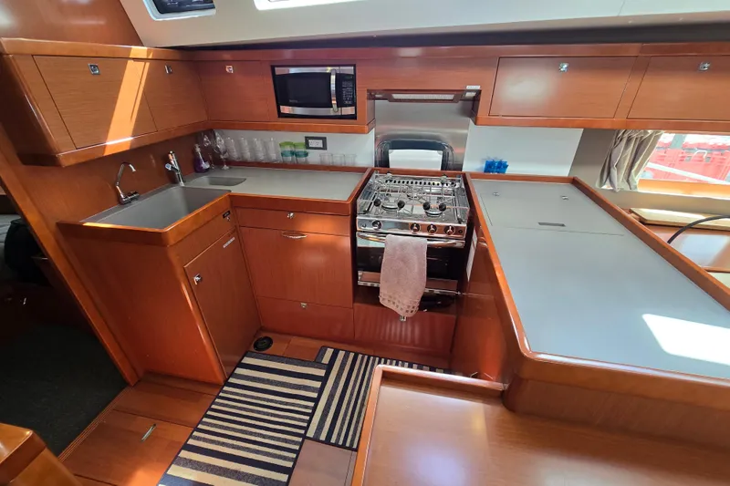 Slide: The Image of Modern kitchen interior of 2016 Beneteau Oceanis 55 yacht with wood cabinetry and appliances. - 57