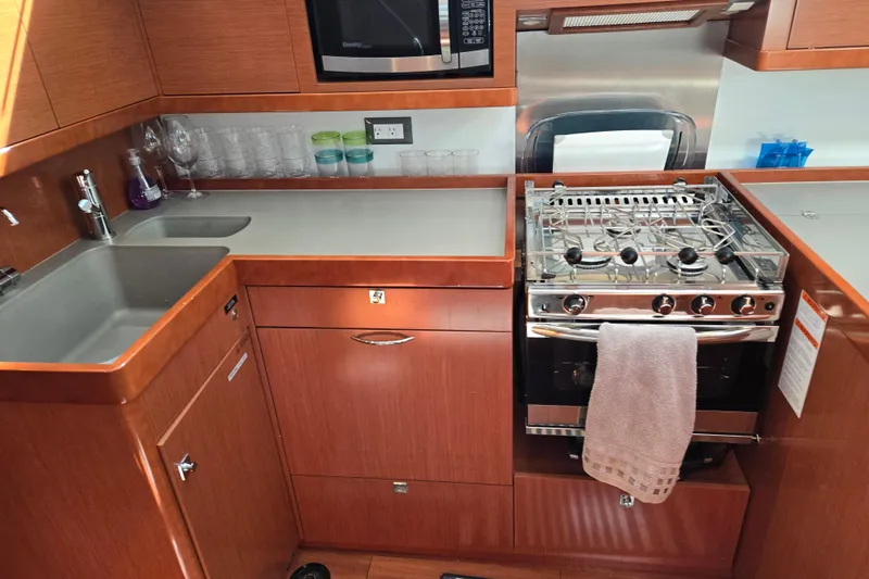 Slide: The Image of Galley kitchen in 2016 Beneteau Oceanis 55 yacht with stove, sink, and microwave. - 58