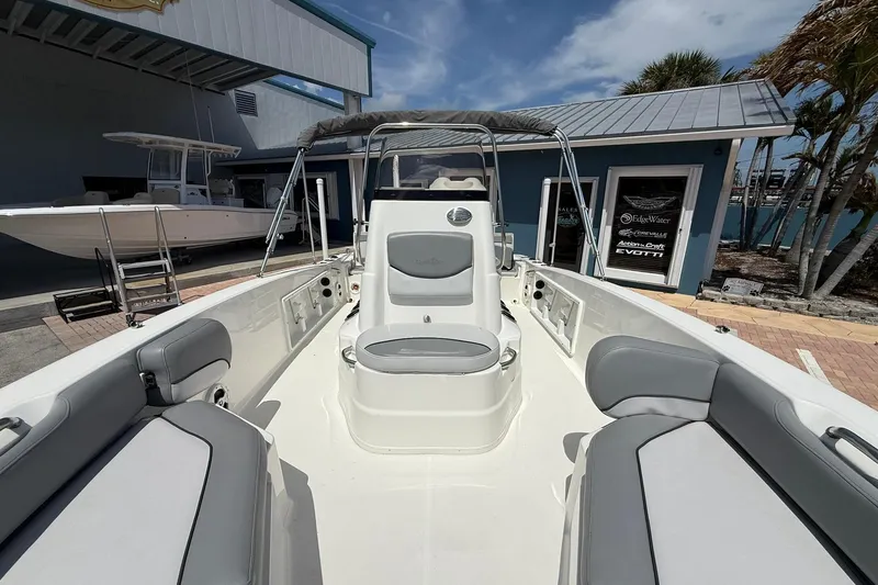 Slide: The Image of 2021 NauticStar 191 Hybrid boat interior with seating, docked near a marina building. - 22
