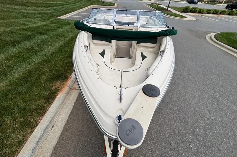 Slide: The Image of 2001 Larson 210 I/O boat parked on a street, featuring a spacious bow seating area. - 4