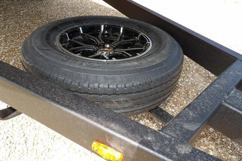 Slide: The Image of Spare tire on Crestliner 1760 Retriever FCC trailer, 2026 model, resting on gravel. - 36