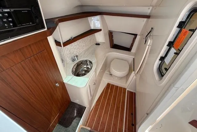 Slide: The Image of 2018 Grady-White Freedom 325 boat interior with wood accents, sink, and toilet. - 12