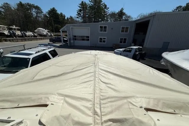 Slide: The Image of 2018 Grady-White Freedom 325 boat with cover, parked near a garage and vehicles. - 15