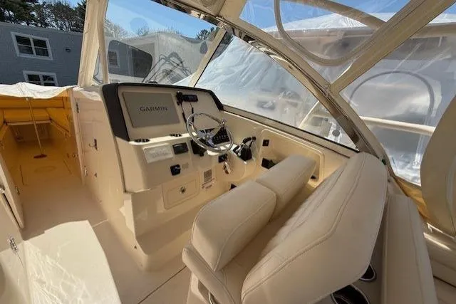 Slide: The Image of 2018 Grady-White Freedom 325 boat interior with helm, Garmin display, and beige seating. - 9