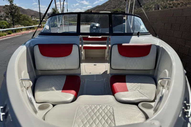 Slide: The Image of 2016 Tahoe 550 TF boat interior with red and white seating, parked outdoors. - 12