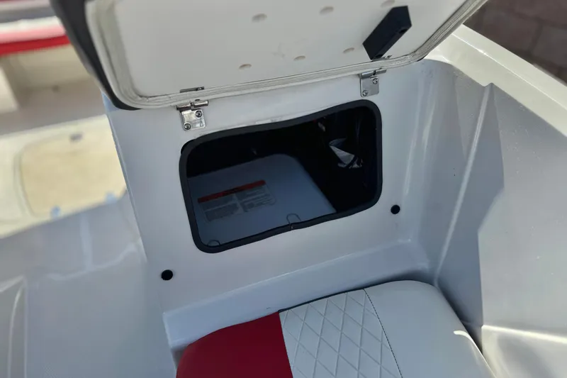 Slide: The Image of Open storage compartment in a 2016 Tahoe 550 TF boat, featuring red and white seating. - 17