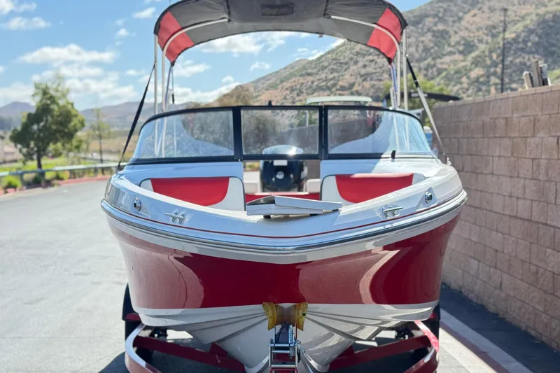 Slide: The Image of 2016 Tahoe 550 TF boat with red and white design, parked outdoors. - 2