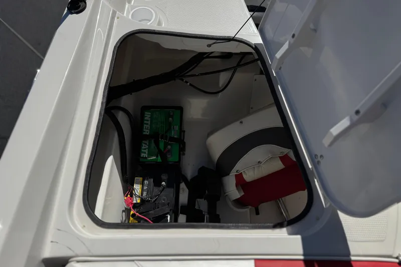 Slide: The Image of Open storage compartment in 2016 Tahoe 550 TF boat, showing battery and life jacket. - 22