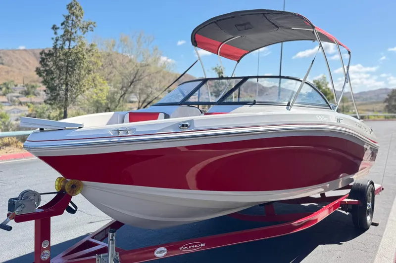 Slide: The Image of Red 2016 Tahoe 550 TF boat on trailer, parked outdoors under clear blue sky. - 3