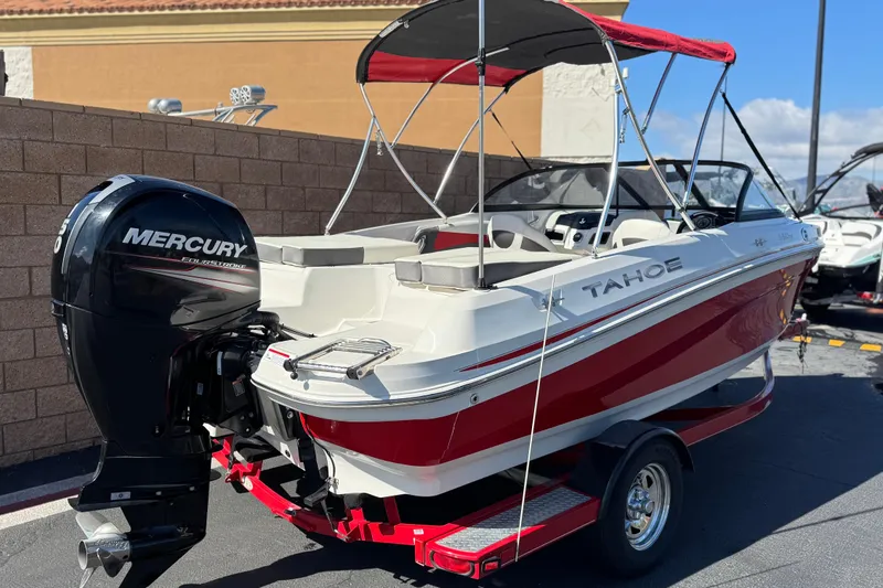 Slide: The Image of 2016 Tahoe 550 TF boat with Mercury engine, red and white design, parked on trailer. - 5