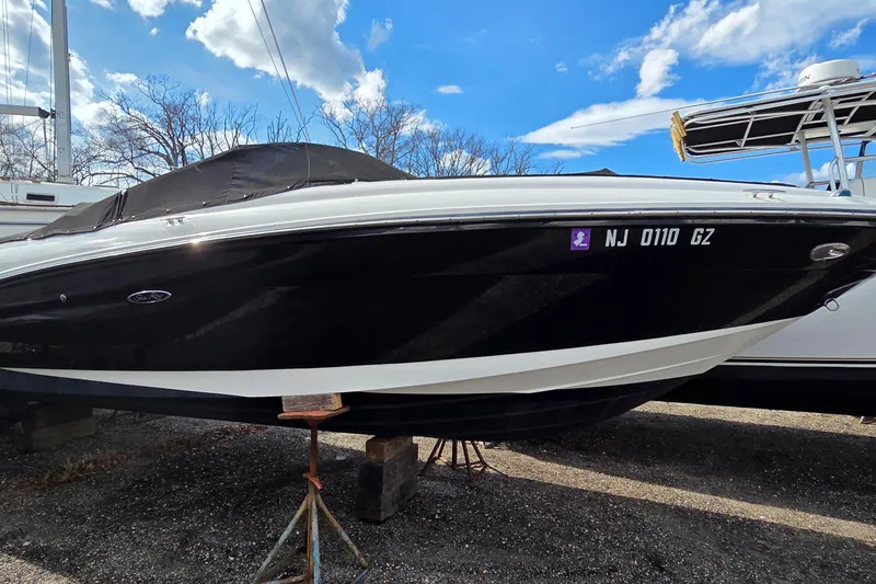 The Image of 2007 Sea Ray SLX 250 boat on stands, black hull, clear sky background. - 0