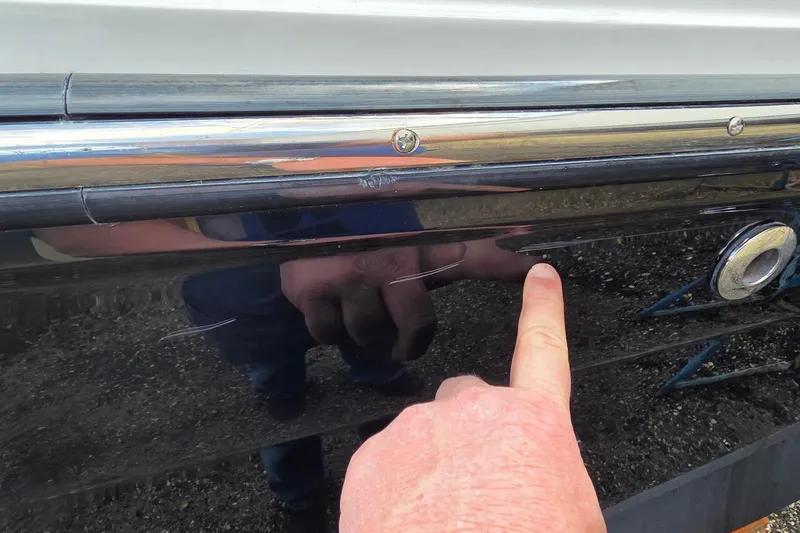 Slide: The Image of Close-up of a 2007 Sea Ray SLX 250 boat with a finger pointing at a scratch. - 25