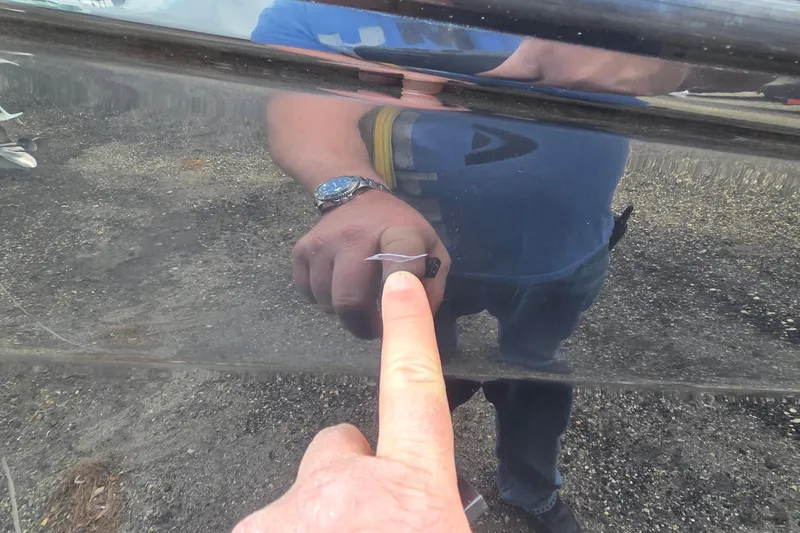 Slide: The Image of Close-up of a person pointing at a scratch on a 2007 Sea Ray SLX 250 boat. - 27