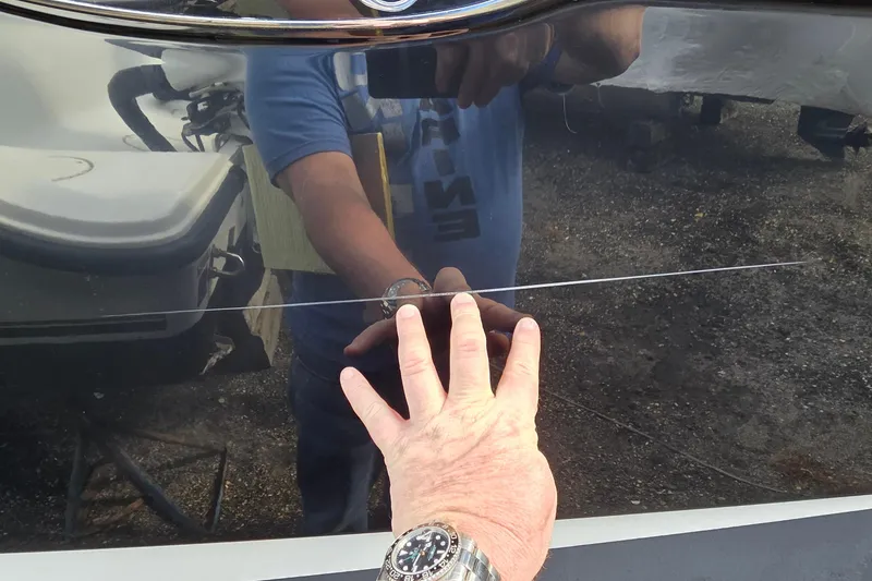 Slide: The Image of Hand inspecting scratch on 2007 Sea Ray SLX 250 boat hull. - 29