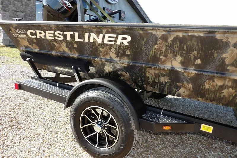 Slide: The Image of 2026 Crestliner 1860 Retriever Deluxe boat with camouflage design on trailer. - 24