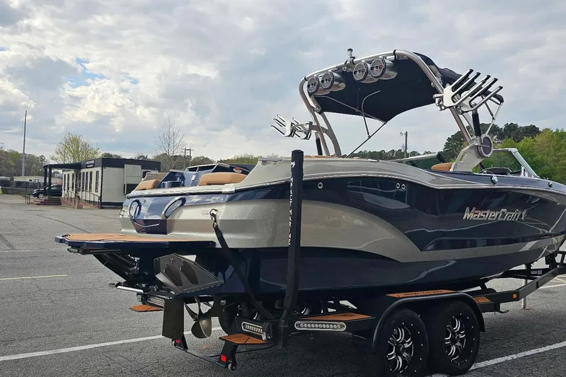 Slide: The Image of 2020 MasterCraft X24 boat on trailer in parking lot under cloudy sky. - 18