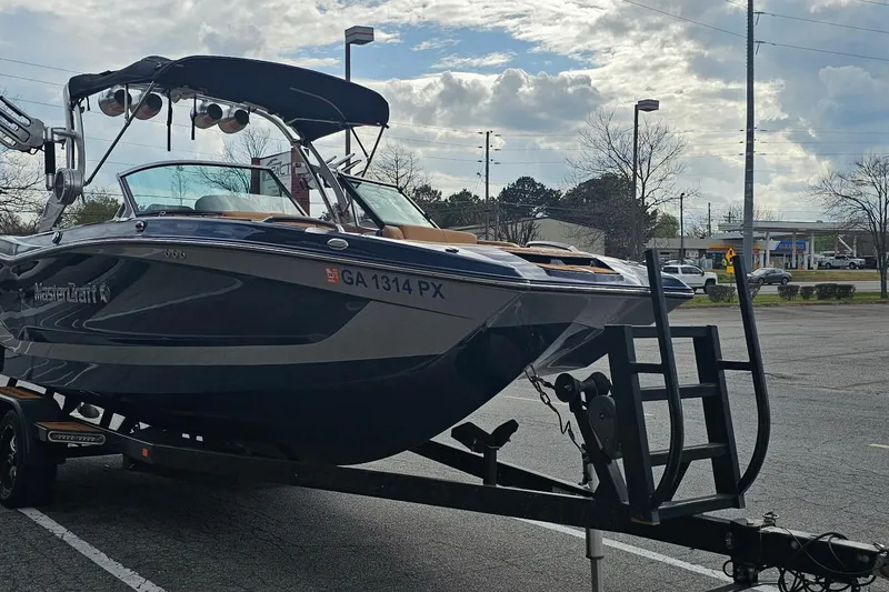 Slide: The Image of 2020 MasterCraft X24 boat on trailer in parking lot under cloudy sky. - 20