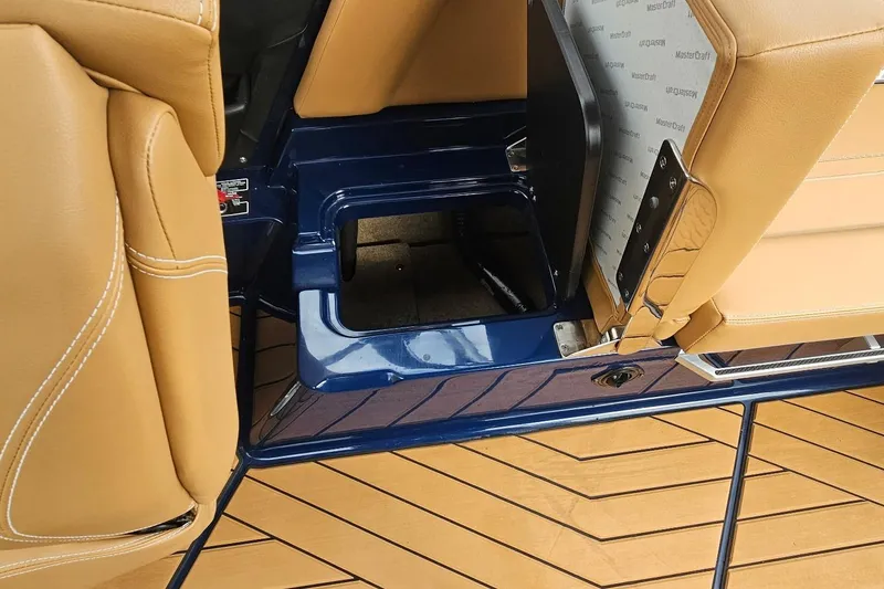Slide: The Image of 2020 MasterCraft X24 boat interior with tan seats and blue storage compartment. - 36