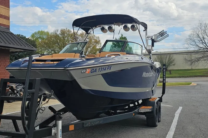 Slide: The Image of 2020 MasterCraft X24 boat on trailer, parked outdoors, featuring sleek design and modern amenities. - 60