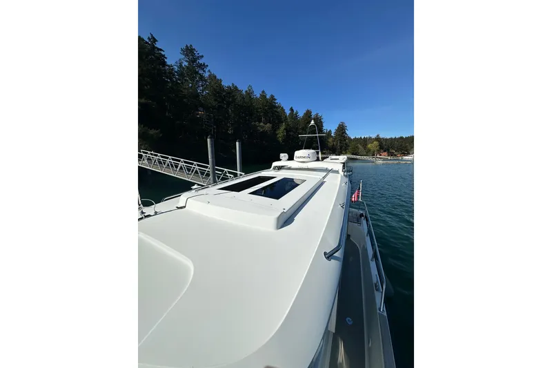 Slide: The Image of 2018 Sargo 25 boat docked by a forested shoreline under clear blue skies. - 11