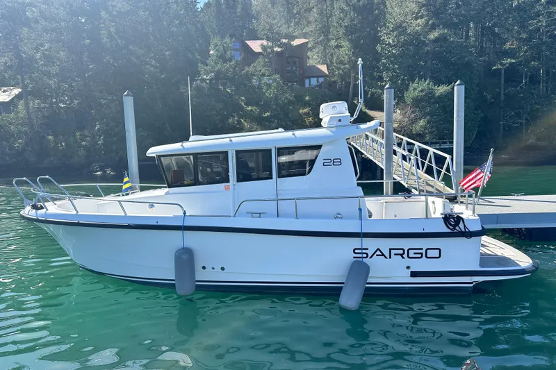 Slide: The Image of 2018 Sargo 25 boat docked in serene waters, surrounded by lush greenery. - 2