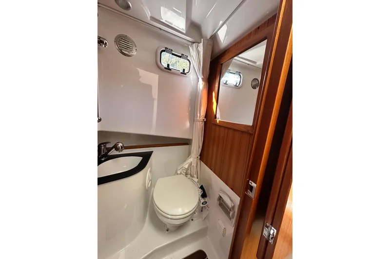 Slide: The Image of Compact bathroom in 2018 Sargo 25 boat with toilet, sink, and wooden accents. - 24