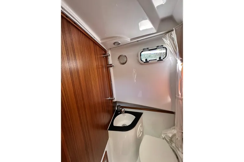 Slide: The Image of Compact bathroom interior of 2018 Sargo 25 boat with wooden accents and porthole window. - 25