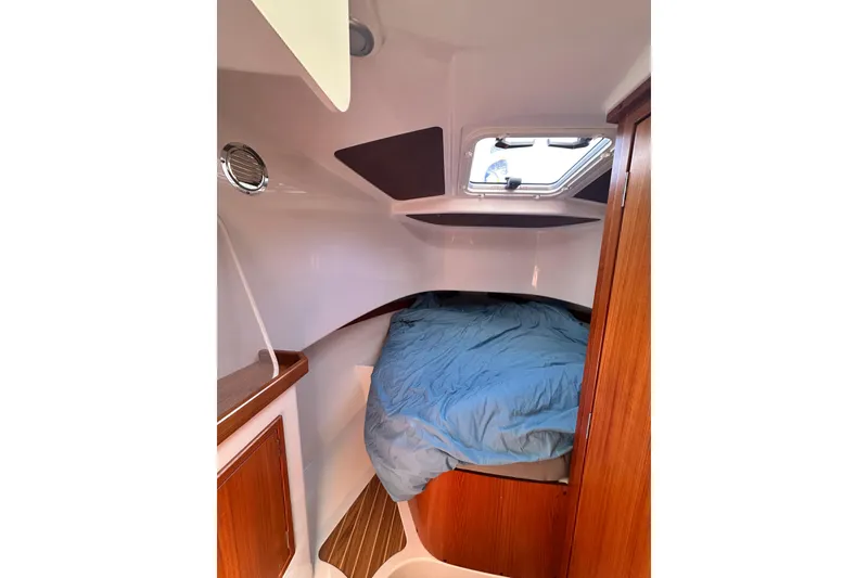 Slide: The Image of Cozy cabin interior of 2018 Sargo 25 boat with wooden accents and blue bedding. - 26