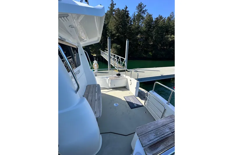 Slide: The Image of 2018 Sargo 25 boat docked, featuring spacious deck and seating, surrounded by lush trees. - 9