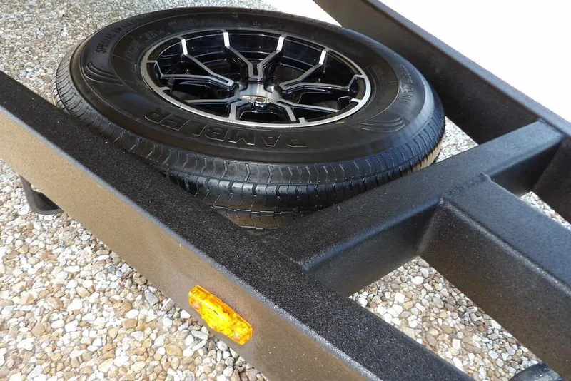 Slide: The Image of Trailer tire on a 2026 Crestliner 1860 Retriever Deluxe, resting on gravel. - 31