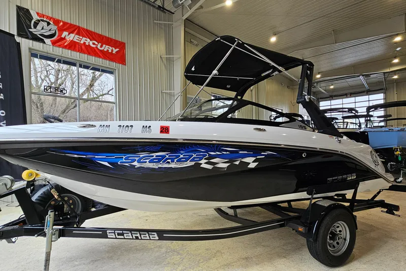 The Image of 2021 Scarab 195 ID boat in showroom, featuring sleek design and vibrant graphics. - 1