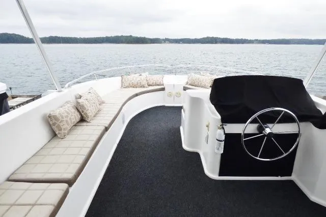 Slide: The Image of 2013 Sumerset 18x85 houseboat deck with seating and steering wheel, overlooking serene lake. - 18