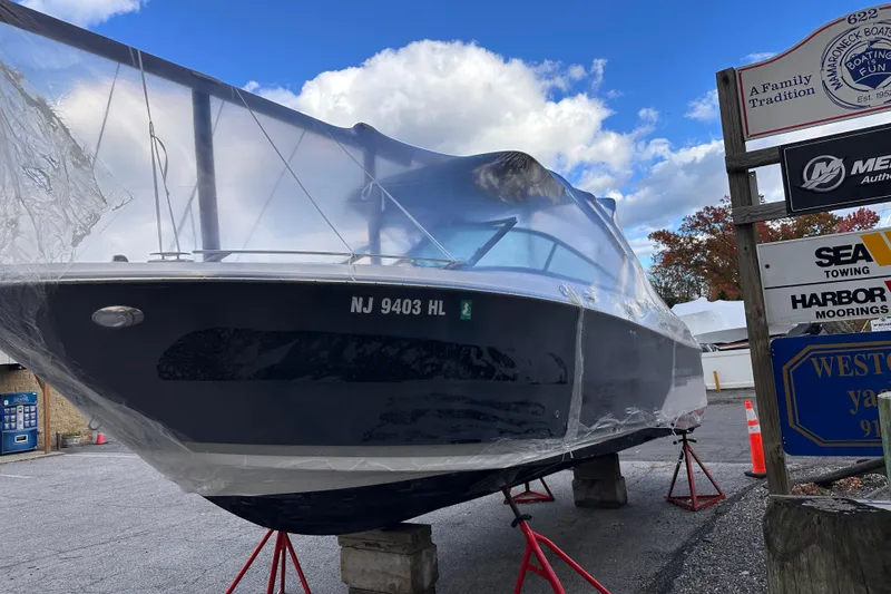 Slide: The Image of 2018 Monterey 258SS Super Sport boat covered in plastic, docked on stands, with clear blue sky. - 6
