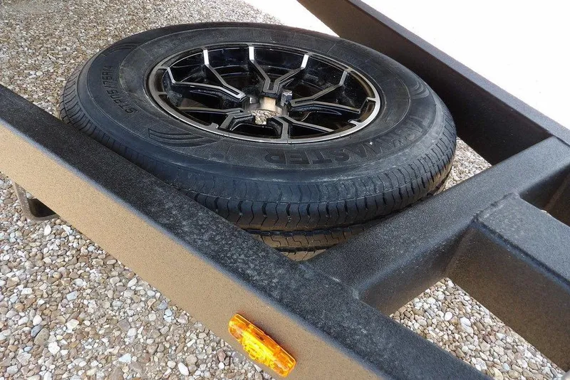 Slide: The Image of Trailer tire on Crestliner 1760 Retriever FCC, 2026 model, resting on gravel surface. - 26