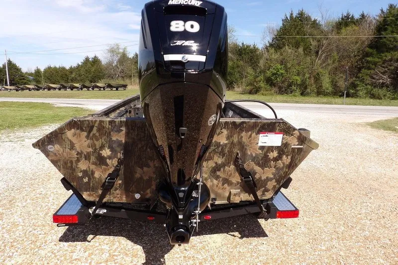 Slide: The Image of 2026 Crestliner 1760 Retriever FCC boat with Mercury 80 engine, camo design, parked outdoors. - 5