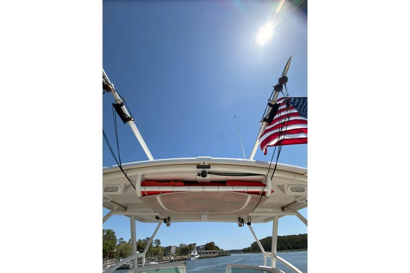 Slide: The Image of 2018 Sailfish 245 DC boat with American flag under clear blue sky. - 23