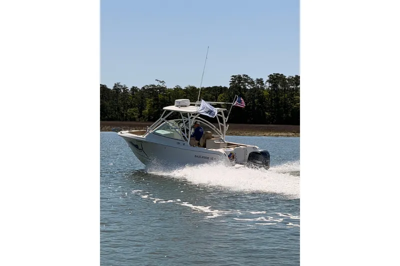 Slide: The Image of 2018 Sailfish 245 DC boat cruising on a sunny day with trees in the background. - 4
