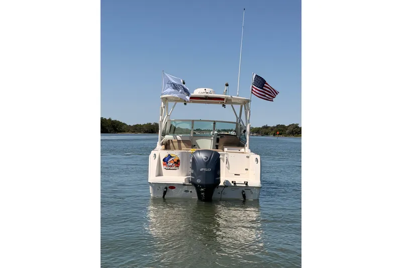 Slide: The Image of 2018 Sailfish 245 DC boat on water with American flag and outboard motor. - 5