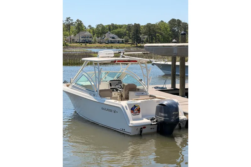 Slide: The Image of 2018 Sailfish 245 DC boat docked, featuring Yamaha 250 engine, serene waterfront setting. - 6