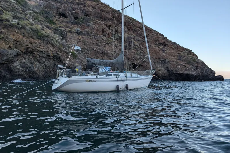Slide: The Image of Sailboat Islander Peterson 40 (1979) anchored near rocky coastline, calm waters. - 3