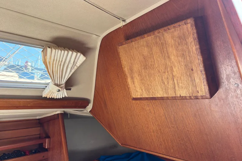 Slide: The Image of Interior of 1979 Islander Peterson 40 sailboat with wooden paneling and window curtain. - 40